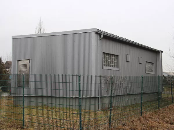 Ein graues Trafohaus mit einer neuen Holzfassade